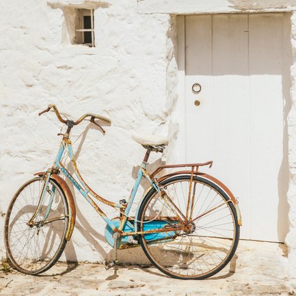 Una bicicletta vintage con dettagli arrugginiti è appoggiata a un muro imbiancato, mettendo in risalto il suo affascinante aspetto consumato dal tempo.